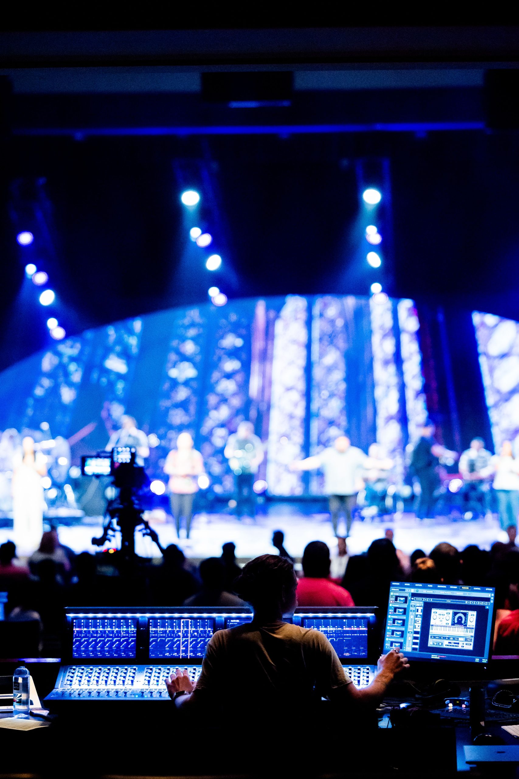 Sound engineer at a live concert, vibrant stage lighting, musical performance.